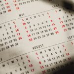 From above of shadows on paper calendar with month inscriptions and dates on sunny day